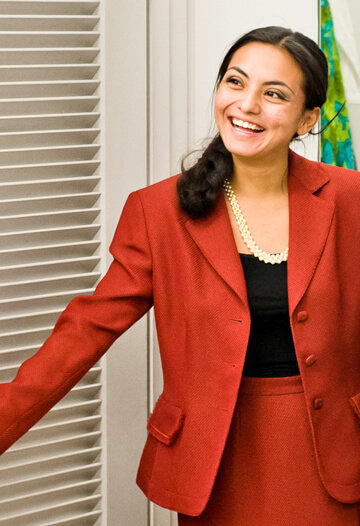 Smiling young woman trying on a red business suit at Goodwill